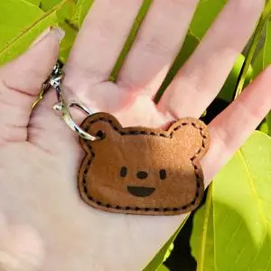 جاسوئیچی چرمی دست‌دوز به شکل خرس، ساخته‌شده از چرم طبیعی قهوه‌ای، با طراحی مینیمال و دوخت دستی زیبا